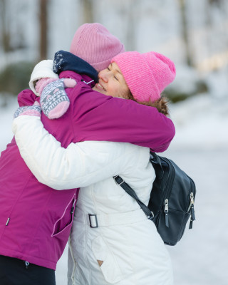 Kaksi naista halaa toisiaan talvimaisemassa. Kaksi naista halaa toisiaan talvimaisemassa.