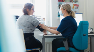 Terveydenhoitaja mittaa asiakkaalta verenpaineen. Terveydenhoitaja mittaa asiakkaalta verenpaineen.