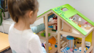 Lapsi leikkii nukketalolla. Lapsi leikkii nukketalolla.