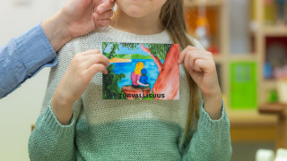 Lapsi näyttää korttia, missä lukee turvallisuus. Lapsi näyttää korttia, missä lukee turvallisuus.